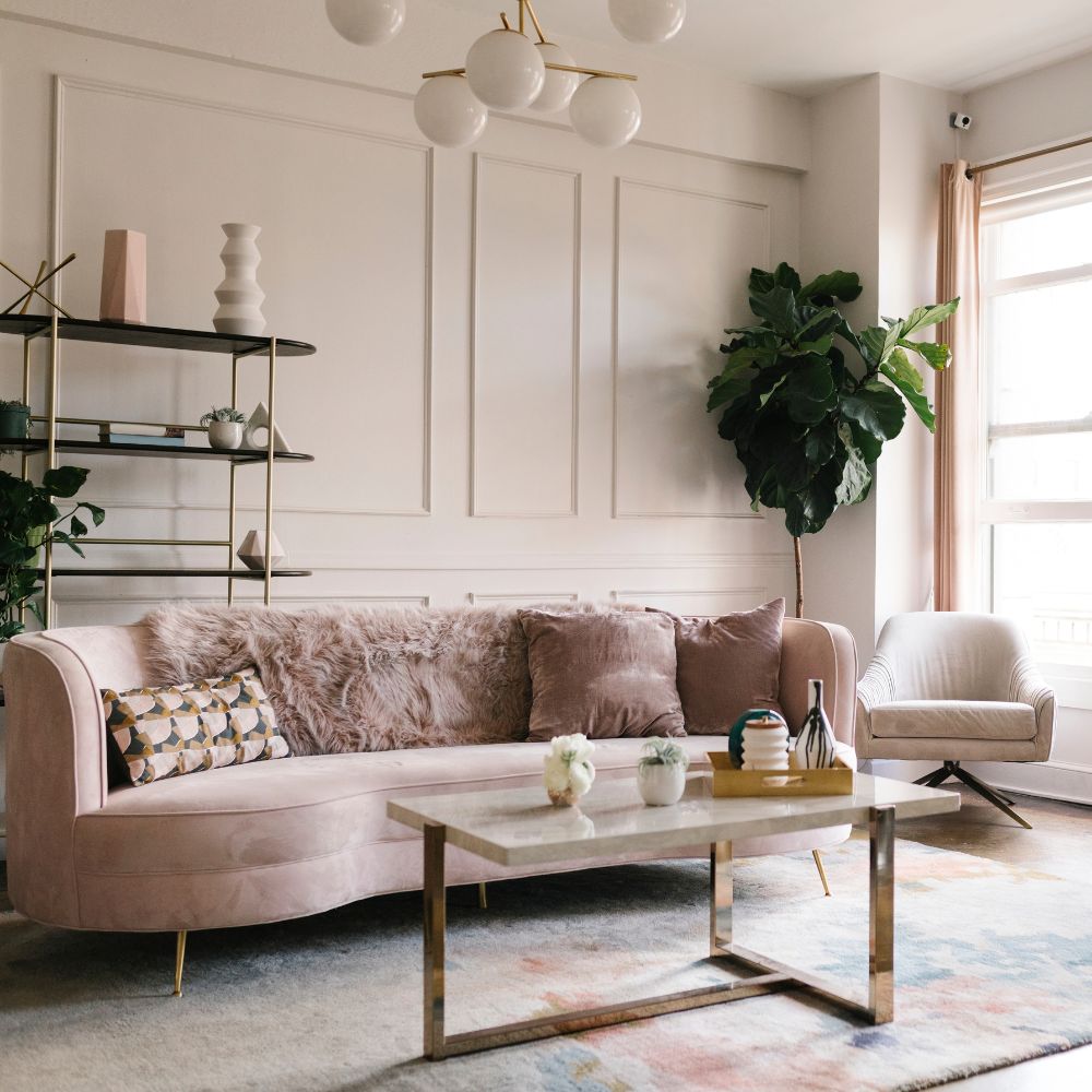 Modern living room with a pink sofa, coffee table, and decorative elements.